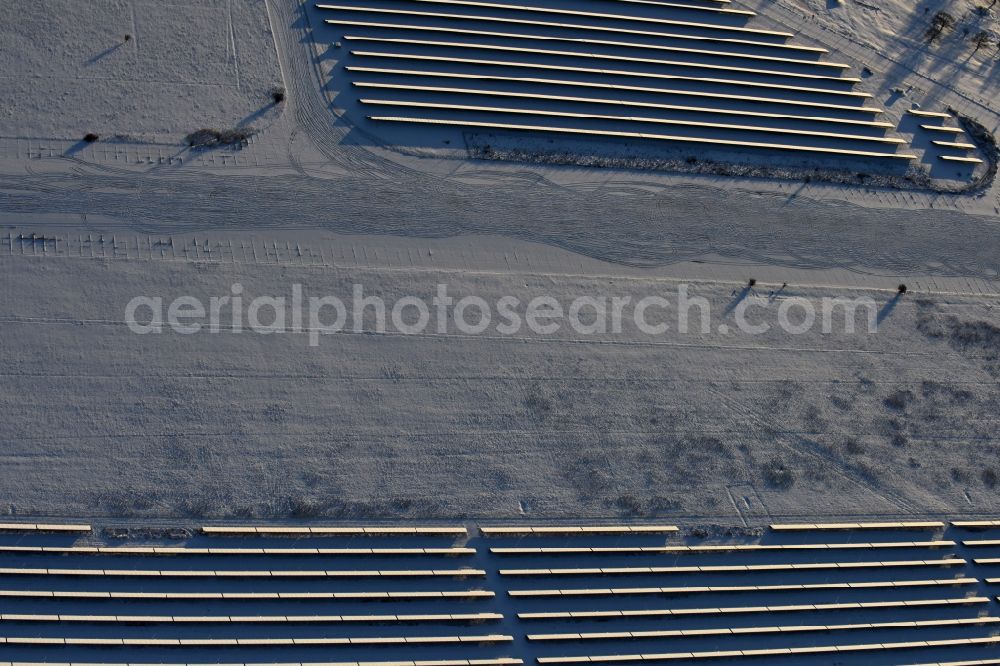 Aerial image Werneuchen - Wintry snowy Panel rows of photovoltaic and solar farm or solar power plant in Werneuchen in the state Brandenburg