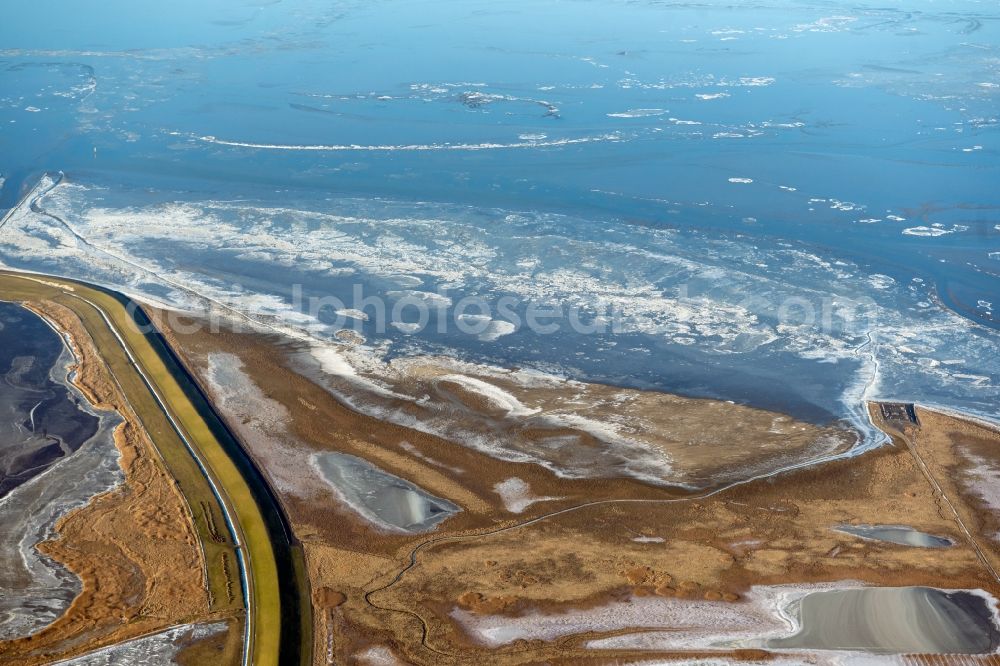 Aerial photograph Krummhörn - Wintry snowy field edge of a target biotope in the field surface in the Leyhoern nature reserve on the Leybucht in the North Sea in Greetsiel in the state Lower Saxony, Germany