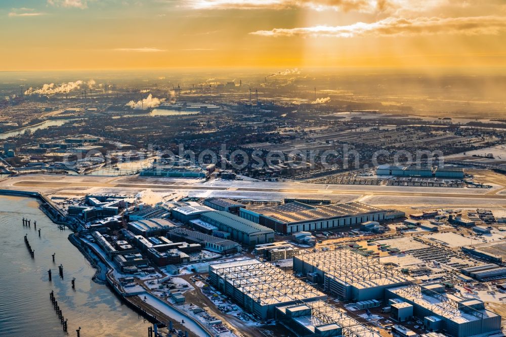 Aerial photograph Hamburg - Wintry snowy sunset at the airbus works and airport of Finkenwerder in Hamburg in Germany. The former Hamburger Flugzeugbau works - on the Finkenwerder Peninsula on the riverbank of the Elbe - include an Airbus production site with an airplane. Several Airbus planes and models are being constructed here