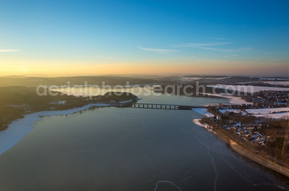 Aerial photograph Möhnesee - Wintry snowy Dam and shore areas at the lake Moehnesee in the state North Rhine-Westphalia