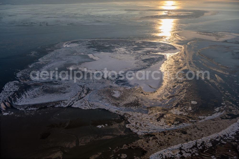 Nordseeinsel Memmert from the bird's eye view: Wintry snowy ice floe pieces of a drift ice layer on the water surface on the Nordseeinsel Memmert at sunset in the state Lower Saxony, Germany