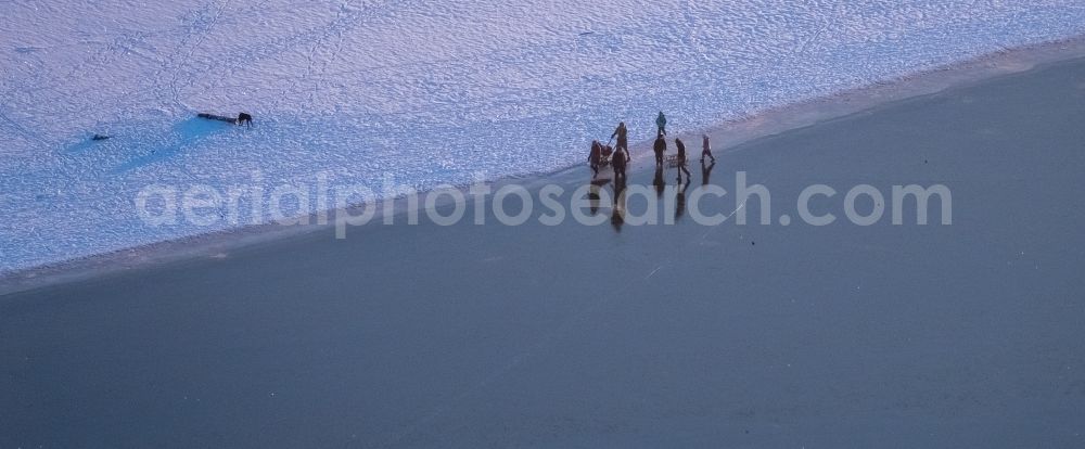 Aerial photograph Möhnesee - Stroller on the wintry snowy and ice-capped bank areas of the Moehnesee in Moehnesee in the federal state North Rhine-Westphalia