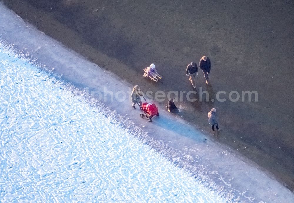 Möhnesee from the bird's eye view: Stroller on the wintry snowy and ice-capped bank areas of the Moehnesee in Moehnesee in the federal state North Rhine-Westphalia