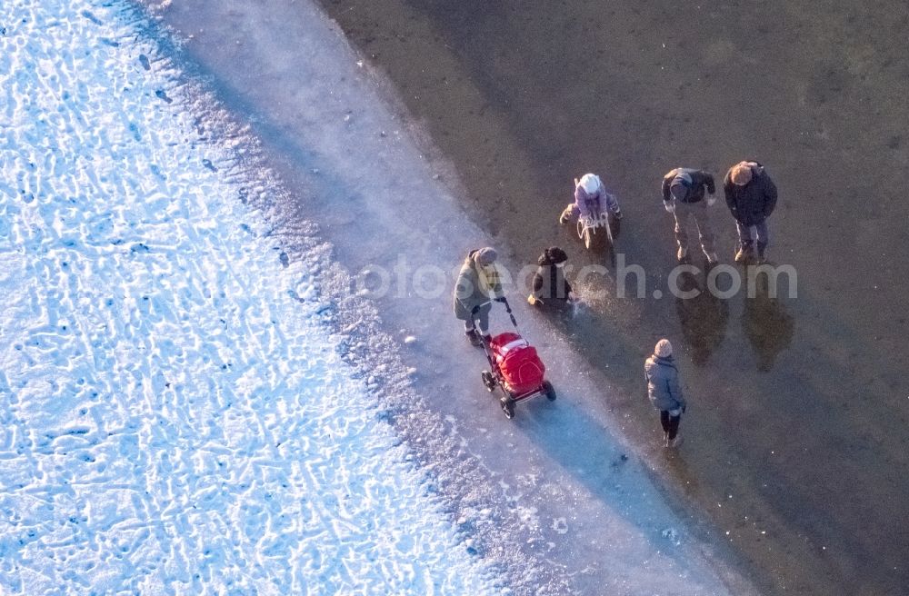 Aerial image Möhnesee - Stroller on the wintry snowy and ice-capped bank areas of the Moehnesee in Moehnesee in the federal state North Rhine-Westphalia