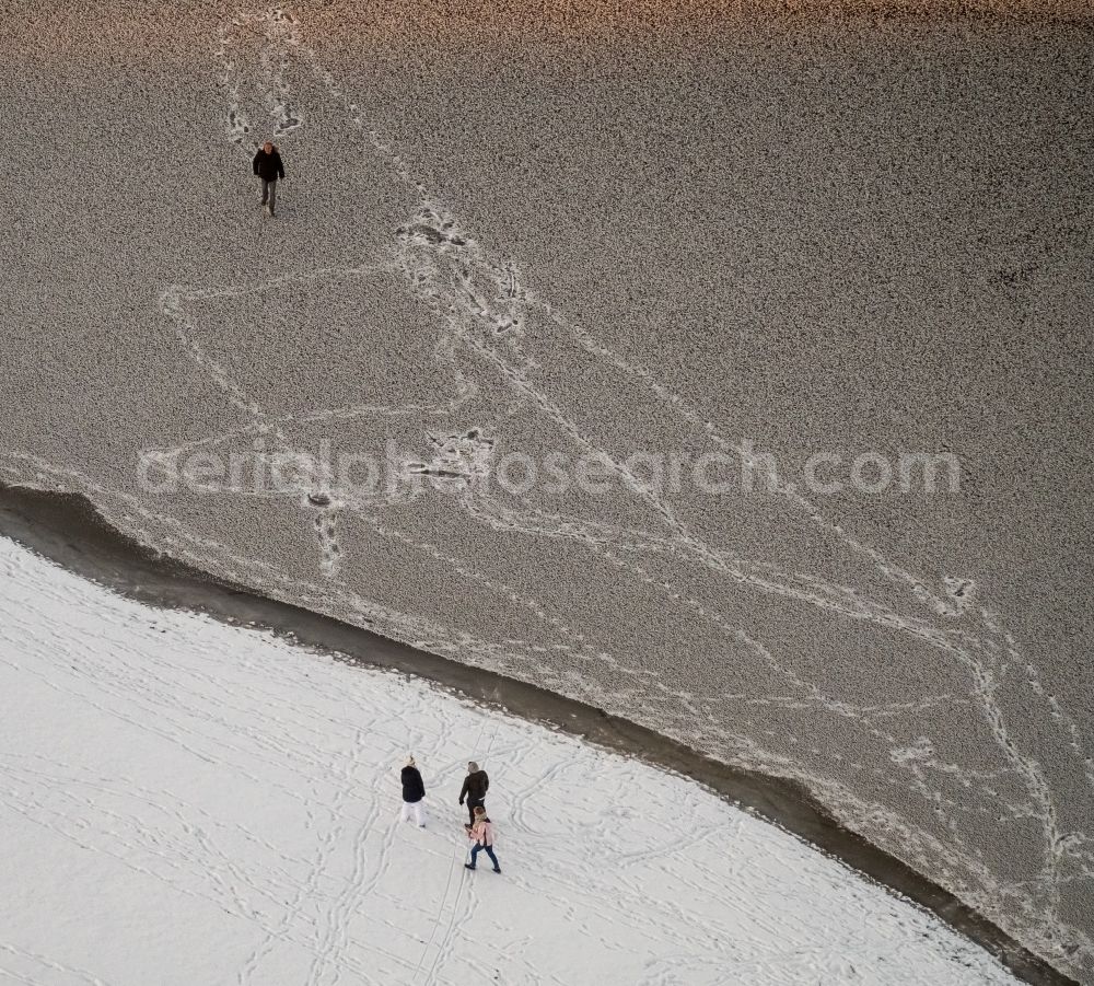 Aerial photograph Möhnesee - Stroller on the wintry snowy and ice-capped bank areas of the Moehnesee in Moehnesee in the federal state North Rhine-Westphalia