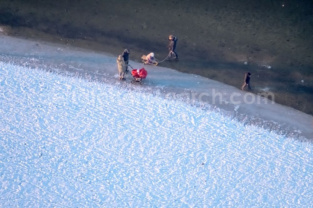 Aerial photograph Möhnesee - Stroller on the wintry snowy and ice-capped bank areas of the Moehnesee in Moehnesee in the federal state North Rhine-Westphalia