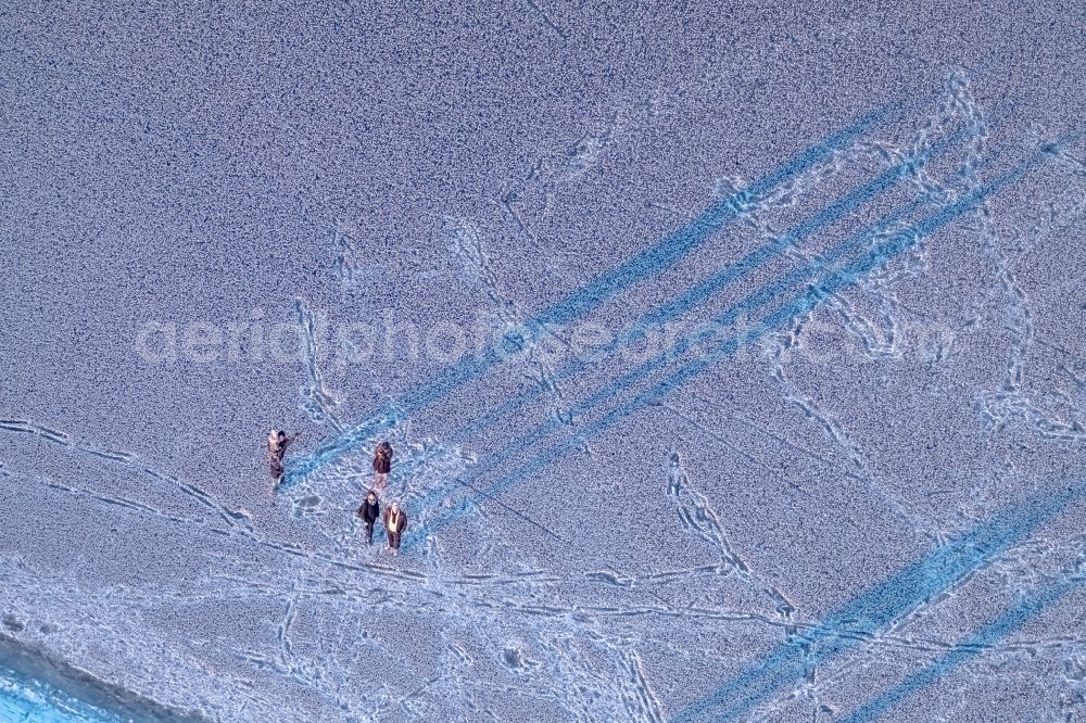 Möhnesee from the bird's eye view: Stroller on the wintry snowy and ice-capped bank areas of the Moehnesee in Moehnesee in the federal state North Rhine-Westphalia