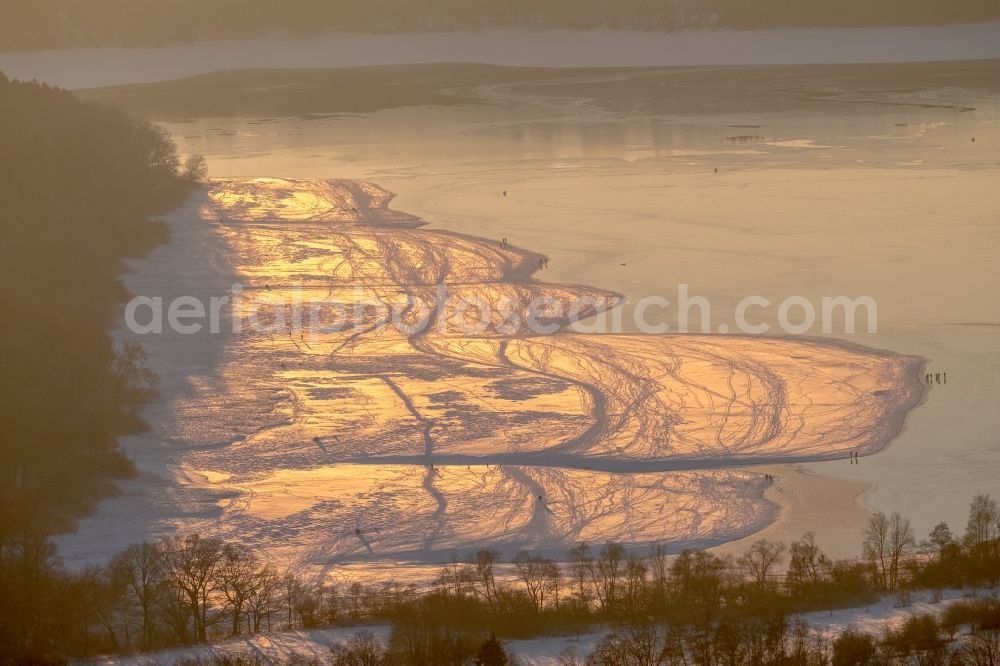 Aerial photograph Möhnesee - Stroller on the wintry snowy and ice-capped bank areas of the Moehnesee in Moehnesee in the federal state North Rhine-Westphalia