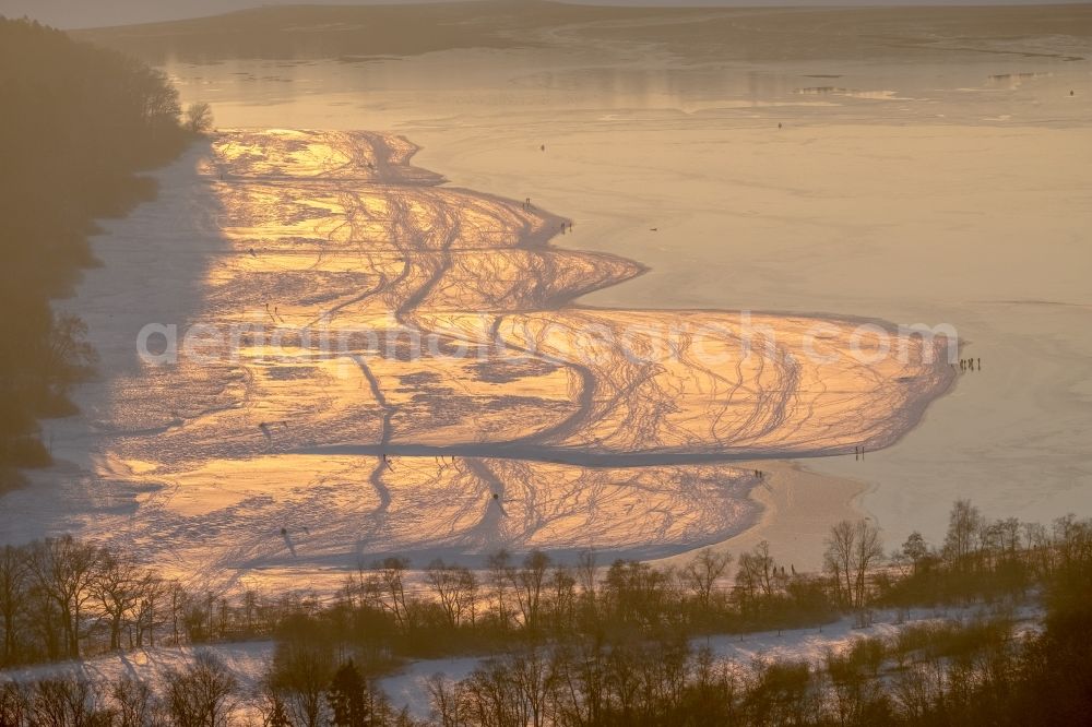 Möhnesee from above - Stroller on the wintry snowy and ice-capped bank areas of the Moehnesee in Moehnesee in the federal state North Rhine-Westphalia