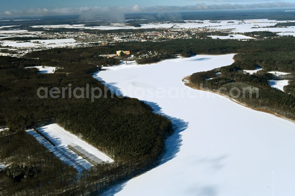 Templin from above - Wintry snowy riparian areas on the lake area of Luebbesee in a forest area in the district Ahrensdorf in Templin in the state Brandenburg, Germany