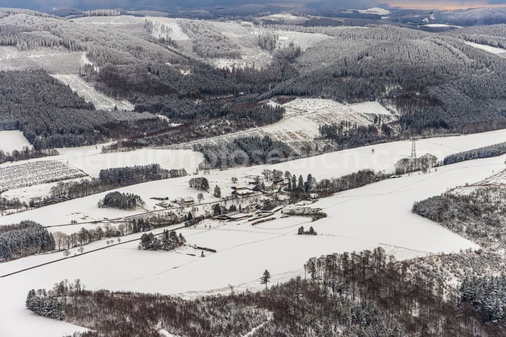 Mosebolle from above - Wintry snowy surrounded by forest and forest areas center of the streets and houses and residential areas in Mosebolle at Sauerland in the state North Rhine-Westphalia, Germany