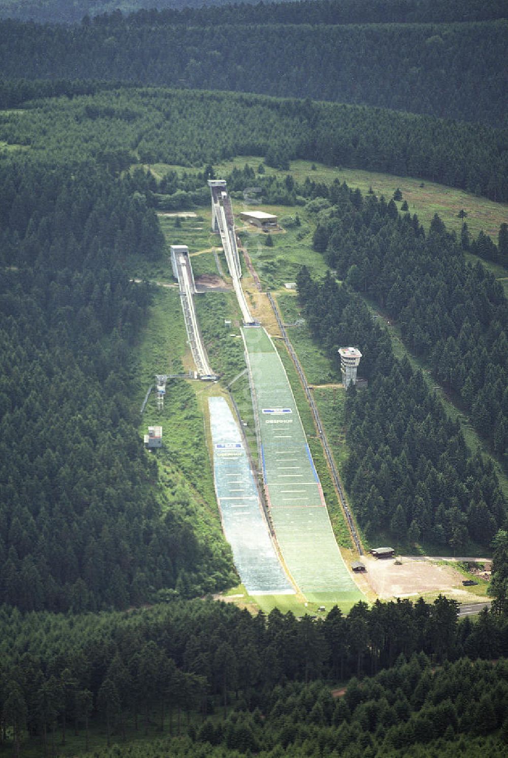 06.06.2003 from the bird's eye view: Die Schanzenanlage im Kanzlersgrund (auch Hans-Renner-Schanze, Rennsteigschanze oder Schanze am Rennsteig genannt) ist eine Skisprunganlage im Oberhofer Kanzlersgrund in Thüringen. Es handelt sich um eine Doppelschanzenanlage mit einer Groß- und einer Normalschanze. Die Hans-Renner-Schanze (Baujahr 1959 bis 1961) hat eine Hillsize von 140 und die Rennsteigschanze (Baujahr 1983 bis 1987) von 96 Metern.Die Hans-Renner-Schanze war die größte Skisprungschanze der DDR und zählt heute zu den größten Schanzen der Welt.