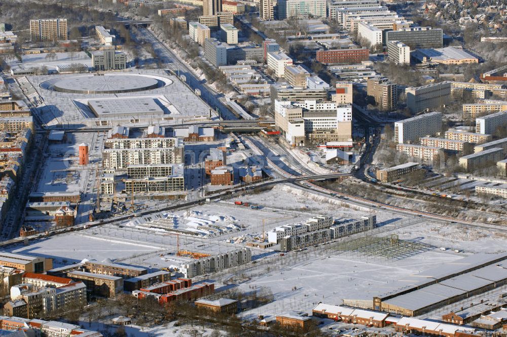 Berlin from above - Winterstimmung am schneebedecktem Geländes des ehemaligen alten Schlachthofes an der Eldenaer Strasse in Berlin. 90er Jahren neue Pläne entworfen, die auf dem 50 Hektar großen Gelände bis zum Jahr 2010 das neue Stadtquartier Alter Schlachthof mit ca. 250.000 m² gewerblicher Nutzfläche und Wohnungen für 4500 Bewohner entstehen lassen sollen. Das Gelände wurde dazu in fünf neue Areale unterteilt: das Hausburgviertel an der Hausburgstraße im Nordwesten, östlich der Thaerstraße das Thaerviertel, den Blankensteinpark im Zentrum sowie das Eldenaer Viertel und das Pettenkofer Dreieck im Osten. Im Jahr 2000 lebten erst 6 Personen in diesem Gebiet, im Jahr 2004 waren es bereits 430 und derzeit (30. Juni 2008) 521. Auf den einzelnen Baufeldern entstehen neue Townhouses und Stadtvillen; zudem werden weitere Hallen zu Reihenhäusern und Loftwohnungen umgebaut. Alle Neu- und Umbauten sollen bis 2009 abgeschlossen sein. Die stadteigene Entwicklungsgesellschaft SES wurde 2008 bereits aufgelöst. Im Hintergrund das schneebedeckte Geleände des VELEDROMS an der Landsberger Allee, bekannt durch das 6 Tage Rennen.