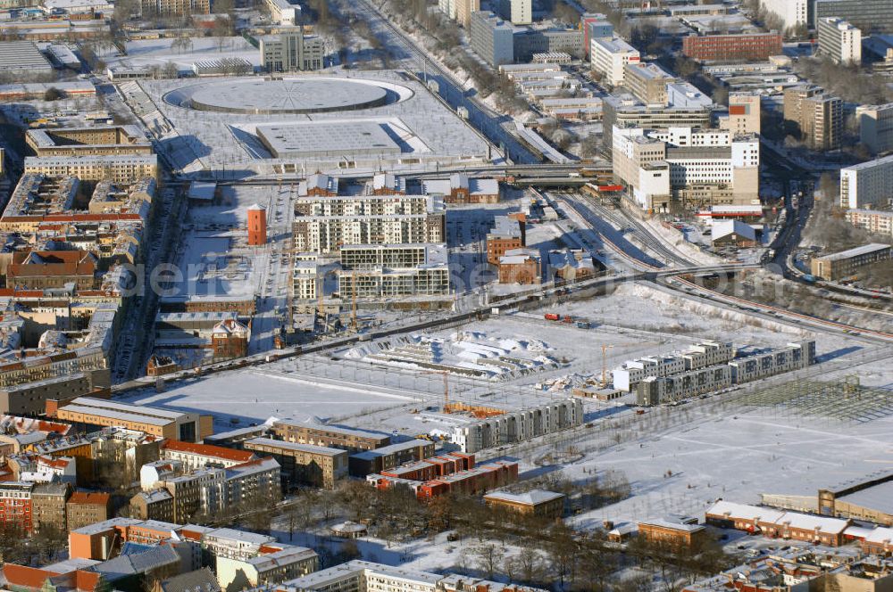 Berlin from the bird's eye view: Winterstimmung am schneebedecktem Geländes des ehemaligen alten Schlachthofes an der Eldenaer Strasse in Berlin. 90er Jahren neue Pläne entworfen, die auf dem 50 Hektar großen Gelände bis zum Jahr 2010 das neue Stadtquartier Alter Schlachthof mit ca. 250.000 m² gewerblicher Nutzfläche und Wohnungen für 4500 Bewohner entstehen lassen sollen. Das Gelände wurde dazu in fünf neue Areale unterteilt: das Hausburgviertel an der Hausburgstraße im Nordwesten, östlich der Thaerstraße das Thaerviertel, den Blankensteinpark im Zentrum sowie das Eldenaer Viertel und das Pettenkofer Dreieck im Osten. Im Jahr 2000 lebten erst 6 Personen in diesem Gebiet, im Jahr 2004 waren es bereits 430 und derzeit (30. Juni 2008) 521. Auf den einzelnen Baufeldern entstehen neue Townhouses und Stadtvillen; zudem werden weitere Hallen zu Reihenhäusern und Loftwohnungen umgebaut. Alle Neu- und Umbauten sollen bis 2009 abgeschlossen sein. Die stadteigene Entwicklungsgesellschaft SES wurde 2008 bereits aufgelöst. Im Hintergrund das schneebedeckte Geleände des VELEDROMS an der Landsberger Allee, bekannt durch das 6 Tage Rennen.