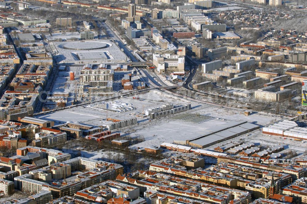 Aerial image Berlin - Winterstimmung am schneebedecktem Geländes des ehemaligen alten Schlachthofes an der Eldenaer Strasse in Berlin. 90er Jahren neue Pläne entworfen, die auf dem 50 Hektar großen Gelände bis zum Jahr 2010 das neue Stadtquartier Alter Schlachthof mit ca. 250.000 m² gewerblicher Nutzfläche und Wohnungen für 4500 Bewohner entstehen lassen sollen. Das Gelände wurde dazu in fünf neue Areale unterteilt: das Hausburgviertel an der Hausburgstraße im Nordwesten, östlich der Thaerstraße das Thaerviertel, den Blankensteinpark im Zentrum sowie das Eldenaer Viertel und das Pettenkofer Dreieck im Osten. Im Jahr 2000 lebten erst 6 Personen in diesem Gebiet, im Jahr 2004 waren es bereits 430 und derzeit (30. Juni 2008) 521. Auf den einzelnen Baufeldern entstehen neue Townhouses und Stadtvillen; zudem werden weitere Hallen zu Reihenhäusern und Loftwohnungen umgebaut. Alle Neu- und Umbauten sollen bis 2009 abgeschlossen sein. Die stadteigene Entwicklungsgesellschaft SES wurde 2008 bereits aufgelöst. Im Hintergrund das schneebedeckte Geleände des VELEDROMS an der Landsberger Allee, bekannt durch das 6 Tage Rennen.