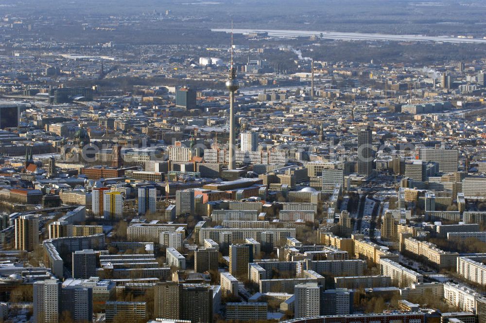 Aerial photograph Berlin - Winterstimmung am schneebedeckter Stadtansicht des Berliner Stadtzentrum Ost mit den Wohngebieten an der Karl-Marx-Allee, dem Berliner Fernsehturm, Rotes Rathaus; Alexanderplatz; Berliner Dom. Im Hintergrund rechts das schneebedeckte Areal des Flughafens Berlin Tegel.