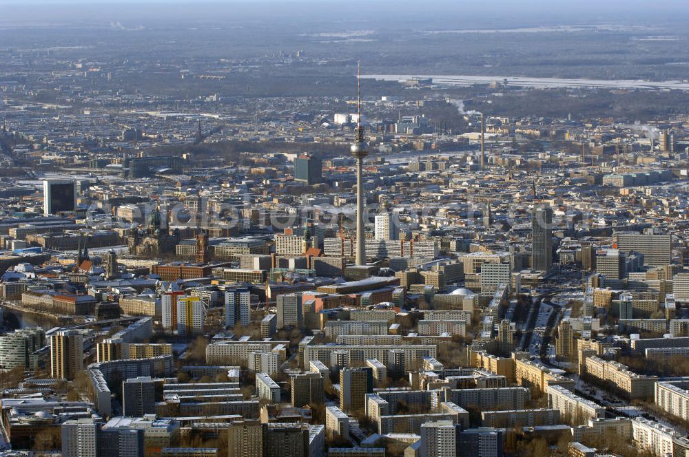 Berlin from above - Winterstimmung am schneebedeckter Stadtansicht des Berliner Stadtzentrum Ost mit den Wohngebieten an der Karl-Marx-Allee, dem Berliner Fernsehturm, Rotes Rathaus; Alexanderplatz; Berliner Dom. Im Hintergrund rechts das schneebedeckte Areal des Flughafens Berlin Tegel.