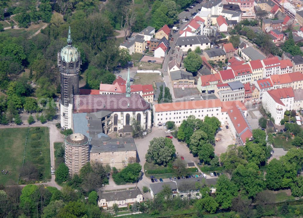 Lutherstadt Wittenberg from the bird's eye view: Blick auf die Schlosskirche Wittenberg. Das Schloss mit seinem 88 m hohen neugotischen Kirchturm am westlichen Ende der Stadt zählt zum wichtigsten UNESCO-Weltkulturerbe. Die erste Erwähnung der Burg stammt von 1187. Im Jahre 1340 bauen die Askanier hier ihr eigenes Schloss. Die Urform der Schlosskirche muss 1496 in solch unzureichendem Zustand gewesen sein, dass nach deren Abriss ein Kirchneubau entstand, der erst 1506 beendet wurde. Berühmtheit erlangte sie, als am 31. Oktober 1517 der bis dahin nahezu unbekannte Wittenberger Augustinermönch und Theologieprofessor Martin Luther seine 95 lateinischen Disputationsthesen verbreitete. Heute befinden sich im Schloss eine Jugendherberge, das Riemer-Museum und die stadtgeschichtlichen Sammlungen.