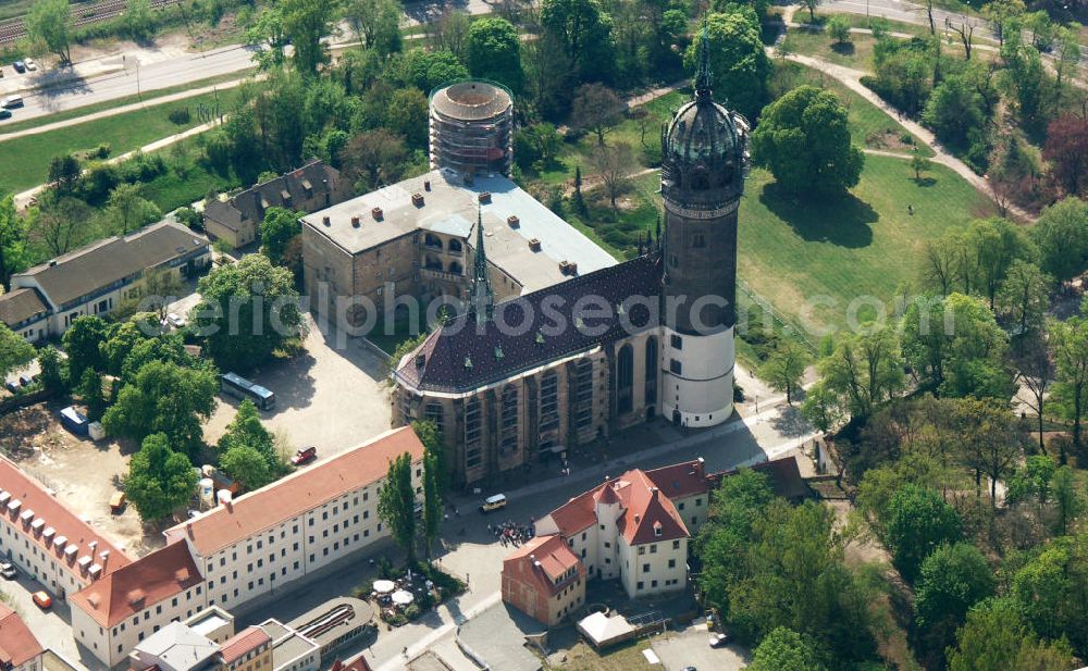 Aerial photograph Lutherstadt Wittenberg - Blick auf die Schlosskirche Wittenberg. Das Schloss mit seinem 88 m hohen neugotischen Kirchturm am westlichen Ende der Stadt zählt zum wichtigsten UNESCO-Weltkulturerbe. Die erste Erwähnung der Burg stammt von 1187. Im Jahre 1340 bauen die Askanier hier ihr eigenes Schloss. Die Urform der Schlosskirche muss 1496 in solch unzureichendem Zustand gewesen sein, dass nach deren Abriss ein Kirchneubau entstand, der erst 1506 beendet wurde. Berühmtheit erlangte sie, als am 31. Oktober 1517 der bis dahin nahezu unbekannte Wittenberger Augustinermönch und Theologieprofessor Martin Luther seine 95 lateinischen Disputationsthesen verbreitete. Heute befinden sich im Schloss eine Jugendherberge, das Riemer-Museum und die stadtgeschichtlichen Sammlungen.