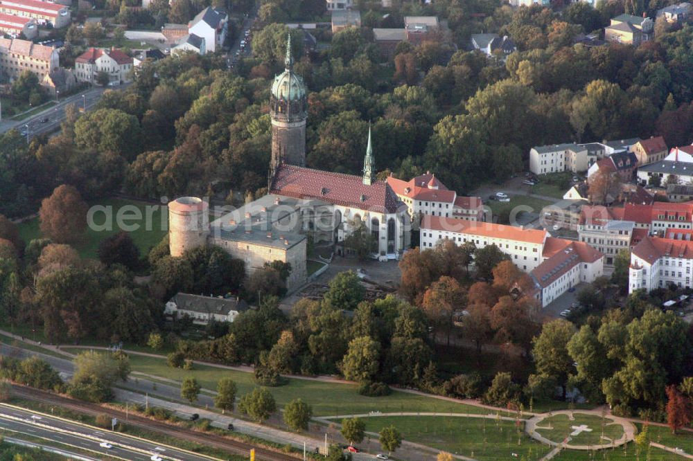 Aerial image Lutherstadt Wittenberg - Blick auf die Schlosskirche Wittenberg. Das Schloss mit seinem 88 m hohen neugotischen Kirchturm am westlichen Ende der Stadt zählt zum wichtigsten UNESCO-Weltkulturerbe. Die erste Erwähnung der Burg stammt von 1187. Im Jahre 1340 bauen die Askanier hier ihr eigenes Schloss. Die Urform der Schlosskirche muss 1496 in solch unzureichendem Zustand gewesen sein, dass nach deren Abriss ein Kirchneubau entstand, der erst 1506 beendet wurde. Berühmtheit erlangte sie, als am 31. Oktober 1517 der bis dahin nahezu unbekannte Wittenberger Augustinermönch und Theologieprofessor Martin Luther seine 95 lateinischen Disputationsthesen verbreitete. Heute befinden sich im Schloss eine Jugendherberge, das Riemer-Museum und die stadtgeschichtlichen Sammlungen. .