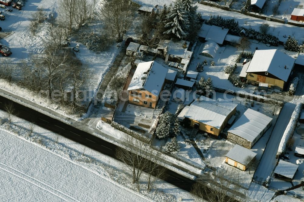 Ahrensfelde from the bird's eye view: Winterly snowy single-family residential area of a settlement besides the road Eichner Chaussee in Ahrensfelde in the state Brandenburg