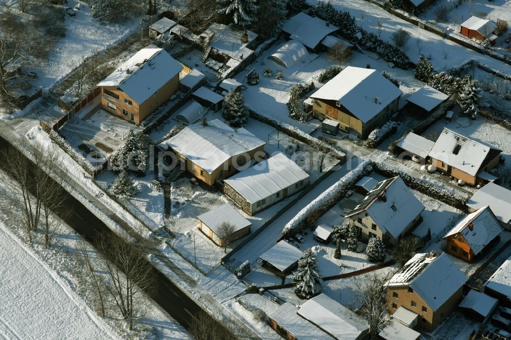 Aerial image Ahrensfelde - Winterly snowy single-family residential area of a settlement besides the road Eichner Chaussee in Ahrensfelde in the state Brandenburg