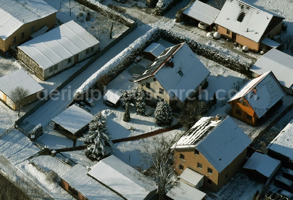 Ahrensfelde from the bird's eye view: Winterly snowy single-family residential area of a settlement besides the road Eichner Chaussee in Ahrensfelde in the state Brandenburg