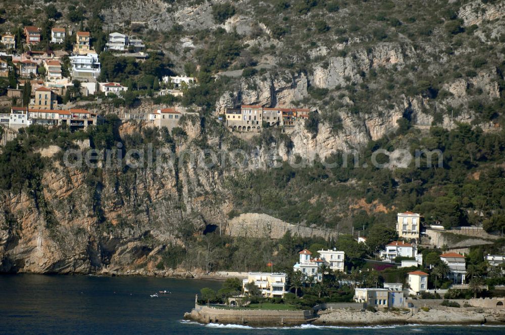 Cap-d' Ail from the bird's eye view: Blick auf ein Wohngebiet an der felsigen Küste und der Avenue Raymond Gramaglia in Cap-d' Ail. Cap-d' Ail ist ein kleiner französischer Badeort an der Cote d' Azur und Grenzort zum Fürstentum Monaco. Die deutsche Übersetzung des Namens lautet „Knoblauchkap“. Der Ort liegt am Fuße des steil aufragenden Bergs Tete de Chien bei La Turbie.