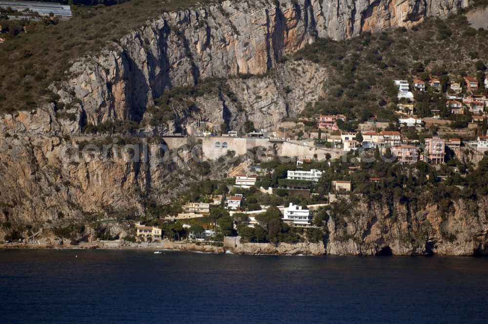 Aerial photograph Cap-d' Ail - Blick auf ein Wohngebiet an der felsigen Küste und der Avenue Raymond Gramaglia in Cap-d' Ail. Cap-d' Ail ist ein kleiner französischer Badeort an der Cote d' Azur und Grenzort zum Fürstentum Monaco. Die deutsche Übersetzung des Namens lautet „Knoblauchkap“. Der Ort liegt am Fuße des steil aufragenden Bergs Tete de Chien bei La Turbie.