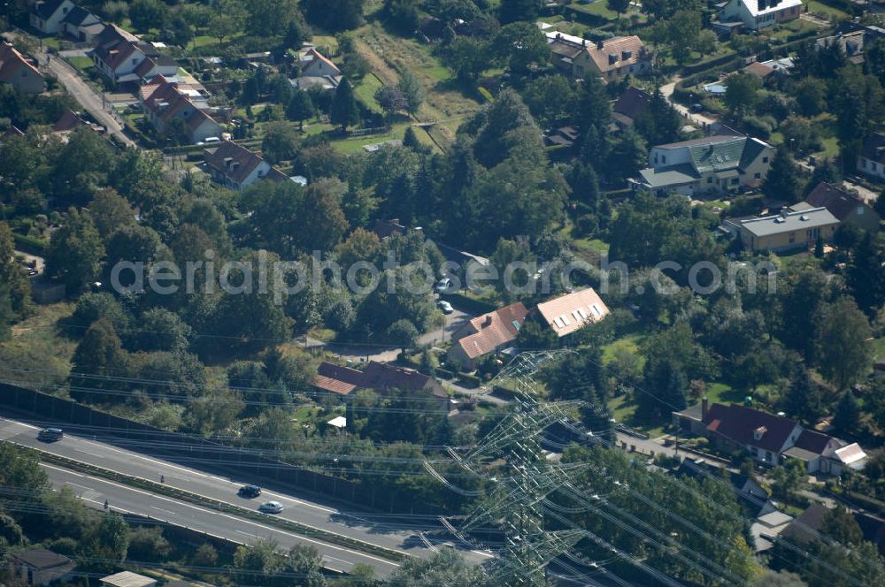 Aerial photograph Berlin - Blick durch eine Stromleitung / Strommast von einer Kleingartensiedlung in Buch über die Autobahn A 10 / E 55 auf Einfamilienhäuser am Siedlungsring in Karow.