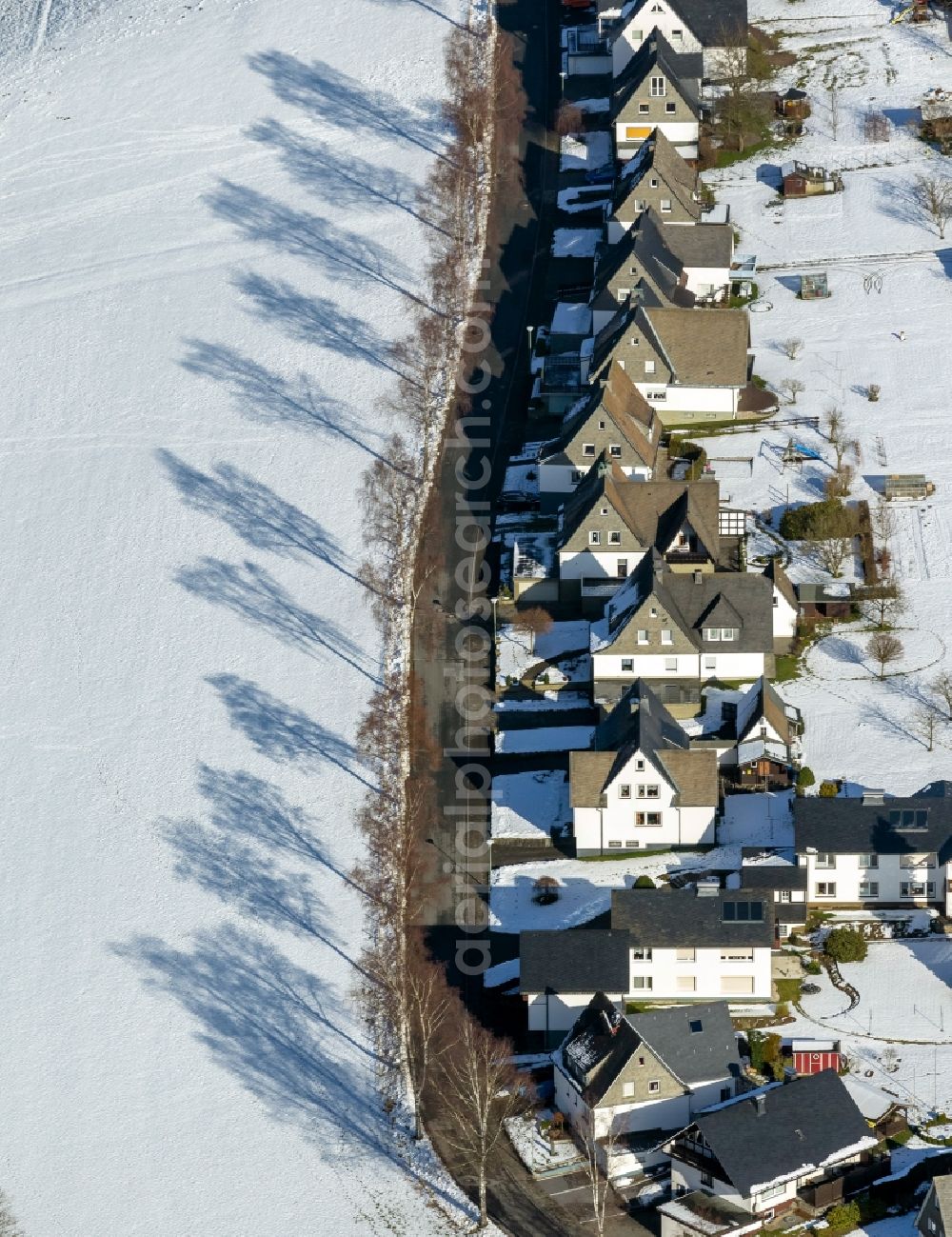 Schmallenberg from above - View of the Kirchstrasse, a residential street with single sided buildings, with tree shadows in the snow in Schmallenberg in the state North Rhine-Westphalia