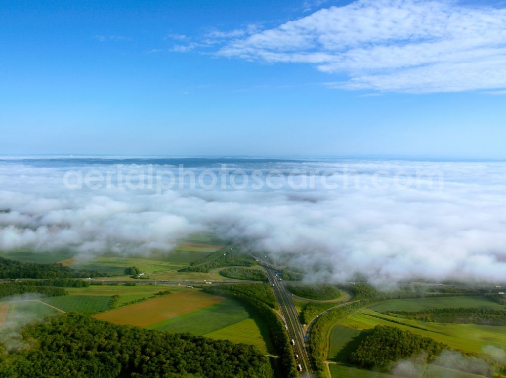 Aerial image Biebelried - Cloud-covered motorway intersection in Biebelried in the state of Bavaria. The junction connects the federal motorways A3 (running East-West) and A7 (North-South). The intersection was built in 1981 as a clover-leaf interchange. It is covered by clouds and surrounded by fields