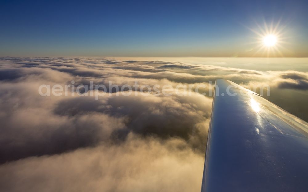 Aerial image Ahlen - Cloud cover and airplane wing above Ahlen in the state of North Rhine-Westphalia. View of the right wing of a plane towards the sun above the clouds