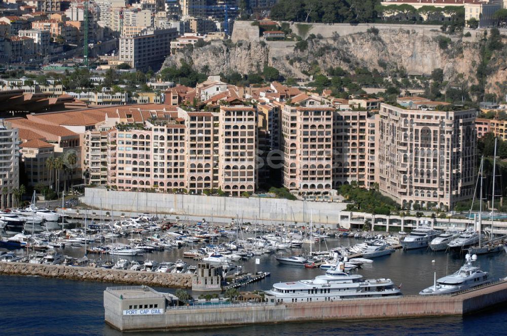 Monaco from above - Blick auf den Yachthafen, Fußballstadion und das Seaside Plaza von Monaco. Das Stadion befindet sich im Stadtteil Fontvieille und wurde im Januar 1985 eröffnet. Die Besonderheit des Stadions ist, das sich das Spielfeld auf 8,5 Meter über der Straßenhöhe befindet, da es auf das viergeschossige Parkhaus gebaut wurde. Mit den großen Rundsäulen hinter den Toren ist die Architektur einzigartig. Das Seaside Plaza ist ein Gebäudekomplex mit extravaganten Apartments zum Verkauf. Touistinfo: Administrative Information Centre, Avenue Albert II 23, MC 98000 Monaco, Tel. +377(0)9898 4026, Fax +377(0)9898 4086, Email: centre-info@gouv.mc; Kontakt Seaside Plaza: Immobilia 2000, Boulevard des Moulins 30, 98000 Monaco, Tel. +377(0)9770055 5, Fax +377(0)9770055 0