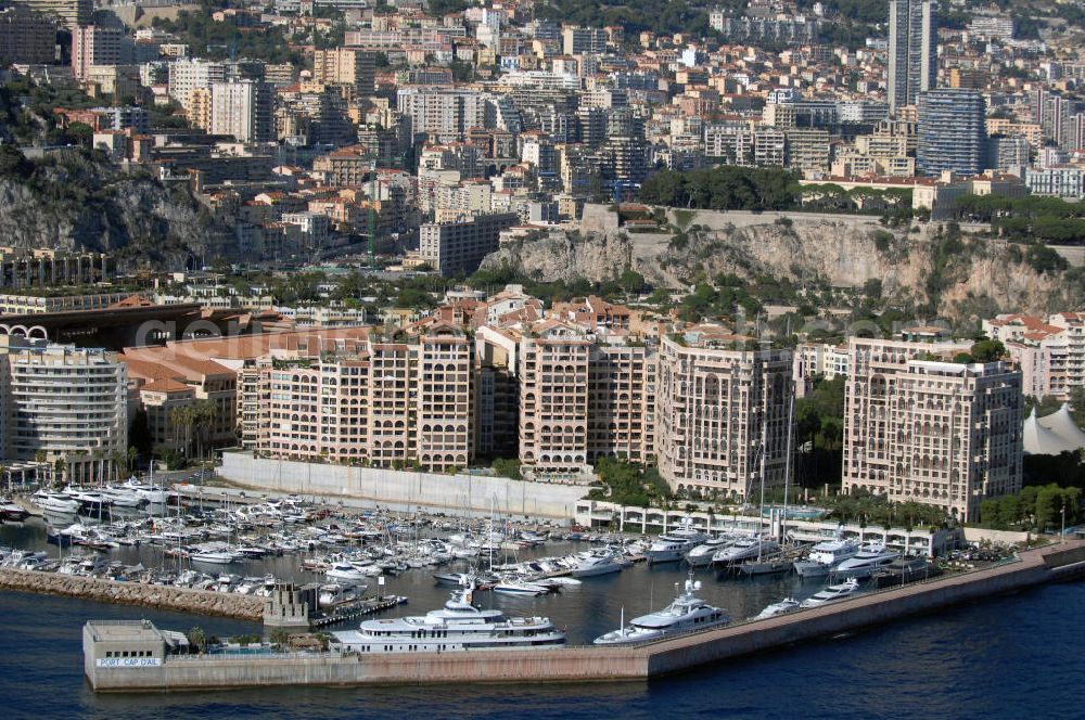 Monaco from the bird's eye view: Blick auf den Yachthafen, Fußballstadion und das Seaside Plaza von Monaco. Das Stadion befindet sich im Stadtteil Fontvieille und wurde im Januar 1985 eröffnet. Die Besonderheit des Stadions ist, das sich das Spielfeld auf 8,5 Meter über der Straßenhöhe befindet, da es auf das viergeschossige Parkhaus gebaut wurde. Mit den großen Rundsäulen hinter den Toren ist die Architektur einzigartig. Das Seaside Plaza ist ein Gebäudekomplex mit extravaganten Apartments zum Verkauf. Touistinfo: Administrative Information Centre, Avenue Albert II 23, MC 98000 Monaco, Tel. +377(0)9898 4026, Fax +377(0)9898 4086, Email: centre-info@gouv.mc; Kontakt Seaside Plaza: Immobilia 2000, Boulevard des Moulins 30, 98000 Monaco, Tel. +377(0)9770055 5, Fax +377(0)9770055 0