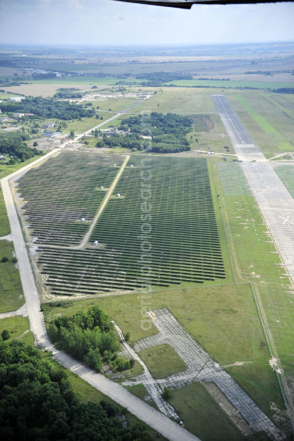 Aerial photograph Tutow - Neuer zweiter Bauabschnitt des Solarenergiepark am Flugplatz Tutow in Mecklenburg - Vorpommern. Die juwi solar GmbH errichtet hier auf ca. 21 Hektar einen Solarpark mit ca. 65.500 Quadratmetern Solarmodulfläche bei ca. 91.000200 Einzelmodulen und einer Nennleistung von ca. 6780 Kilowattstunden jährlich. Modulhersteller ist die First Solar GmbH, die Unterkonstruktionen werden von der Fa. Schletter Leichtmetallbau GmbH errichtet. View of the second section of the solar energy park at the airport Tutow in Mecklenburg - Western Pomerania.